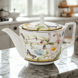 Decorative teapot with floral and butterfly design on a marble countertop.