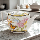 Teapot with floral and butterfly design on a marble surface