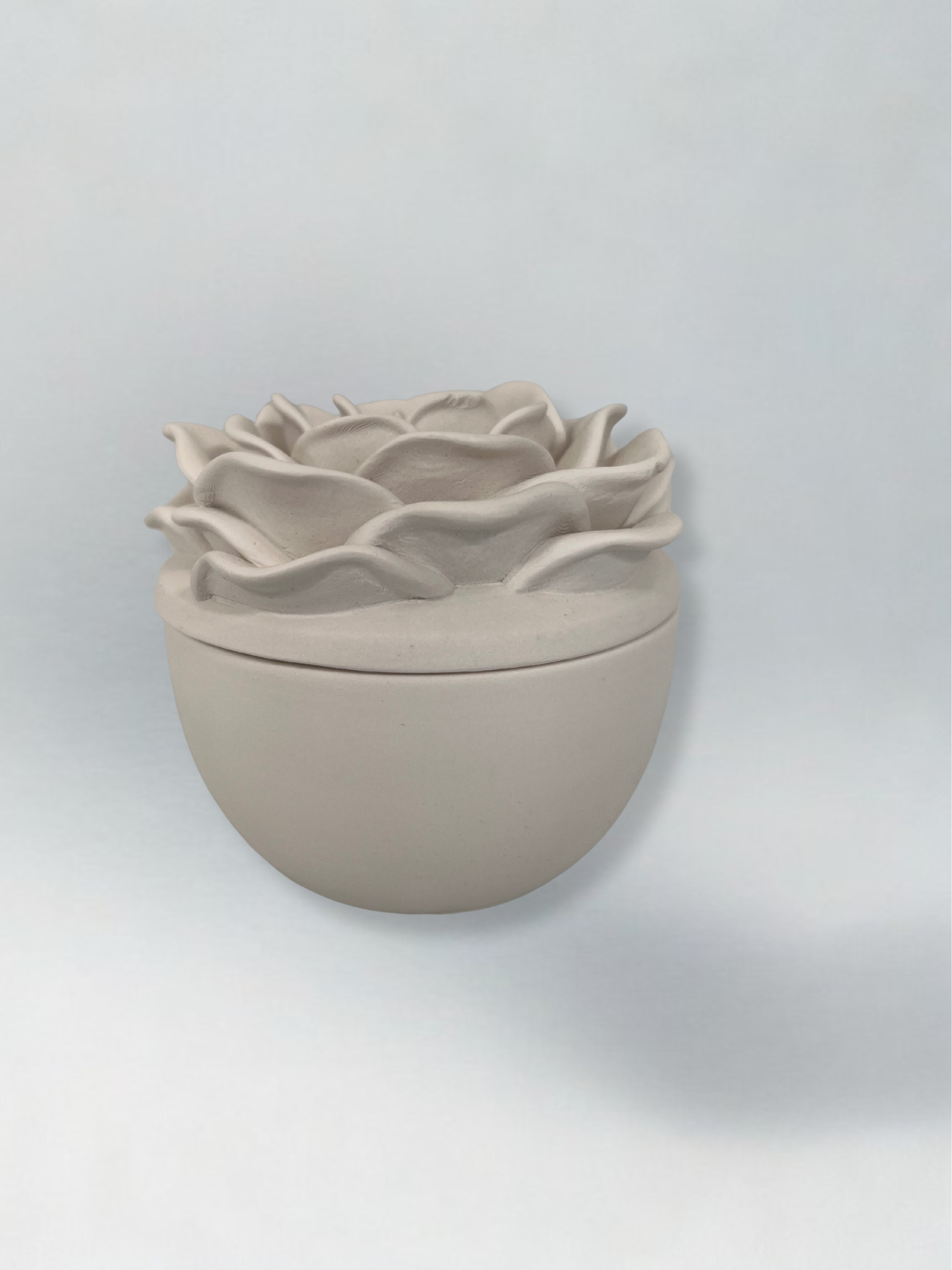 Decorative candle in container with floral designed lid
