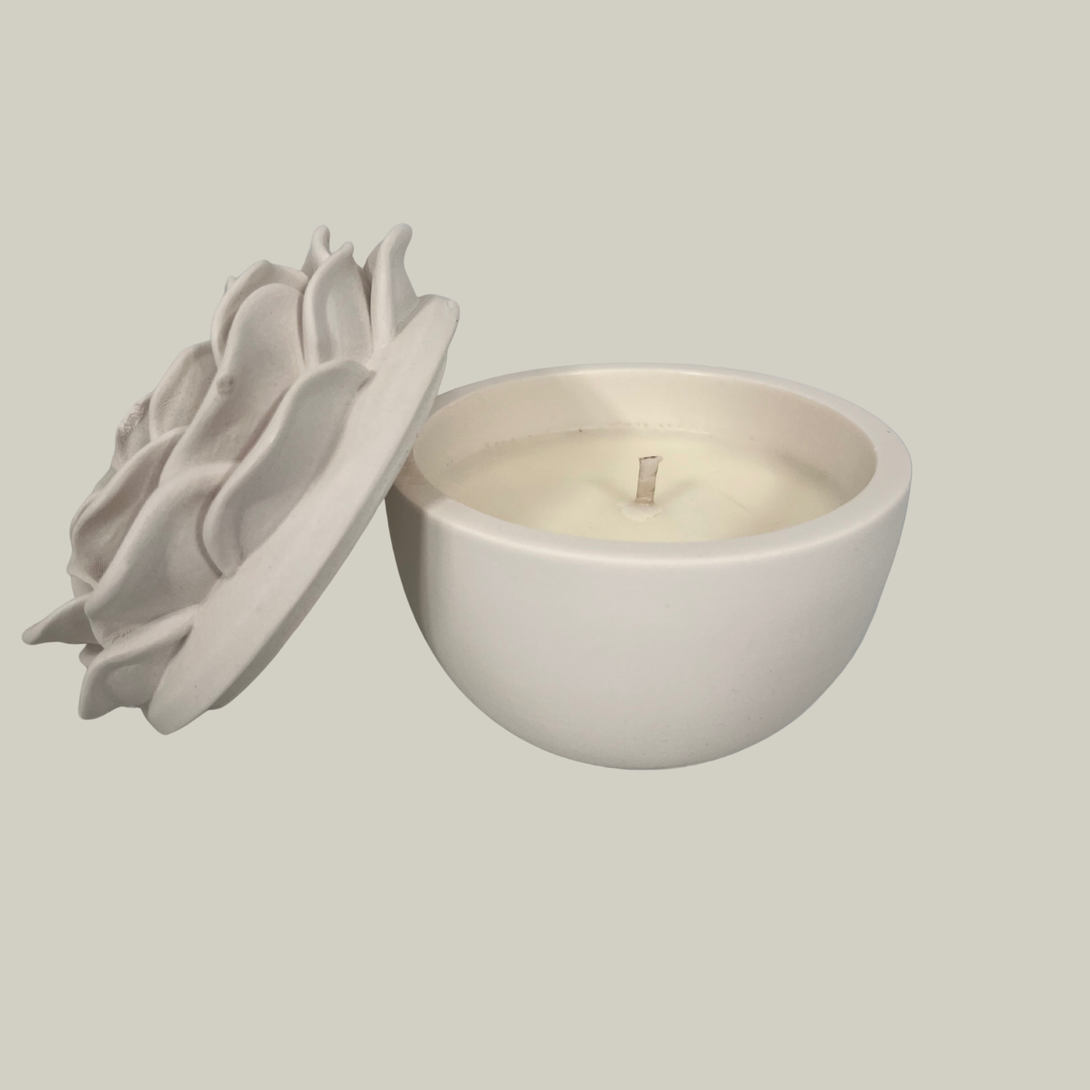 Decorative candle in container with floral designed lid. Lid has been removed.