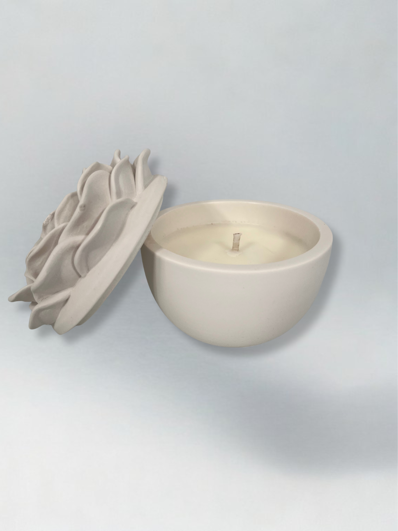 Decorative candle in container with floral designed lid. Lid has been removed.
