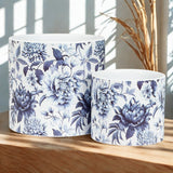 Two ceramic planters with blue floral patterns on a wooden surface.