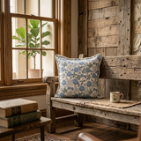 Cozy interior with a wooden bench, floral pillow, and mug near a window.