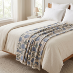 Bedroom with a bed featuring a floral-patterned blanket and white bedding.