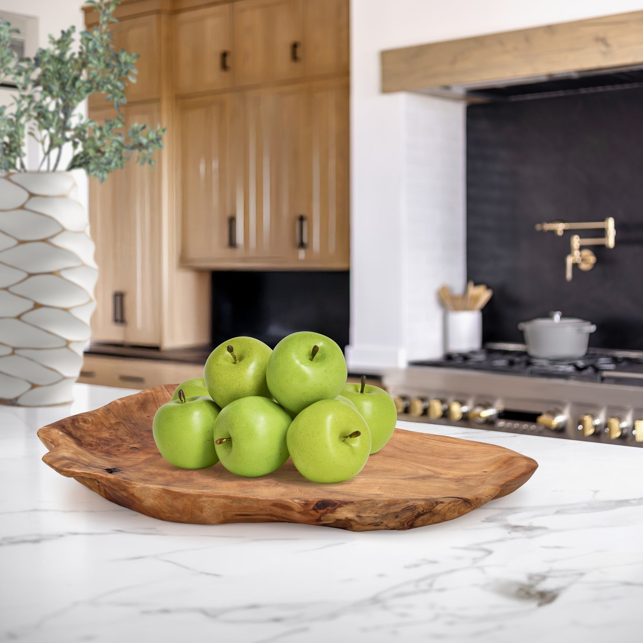 Green apples on a wooden platter in a kitchen