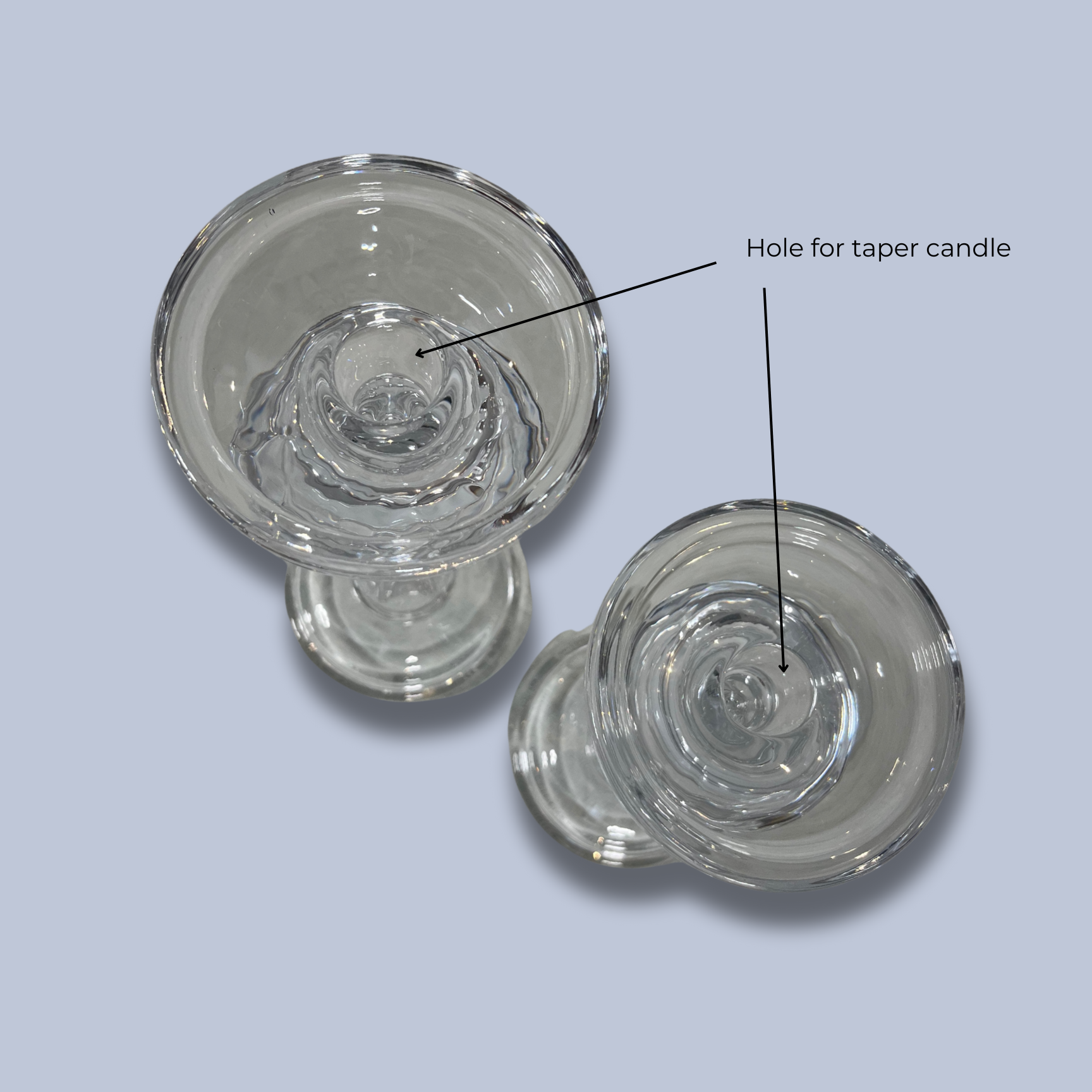 Two glass candle holders with a labeled hole for a taper candle on a light gray background