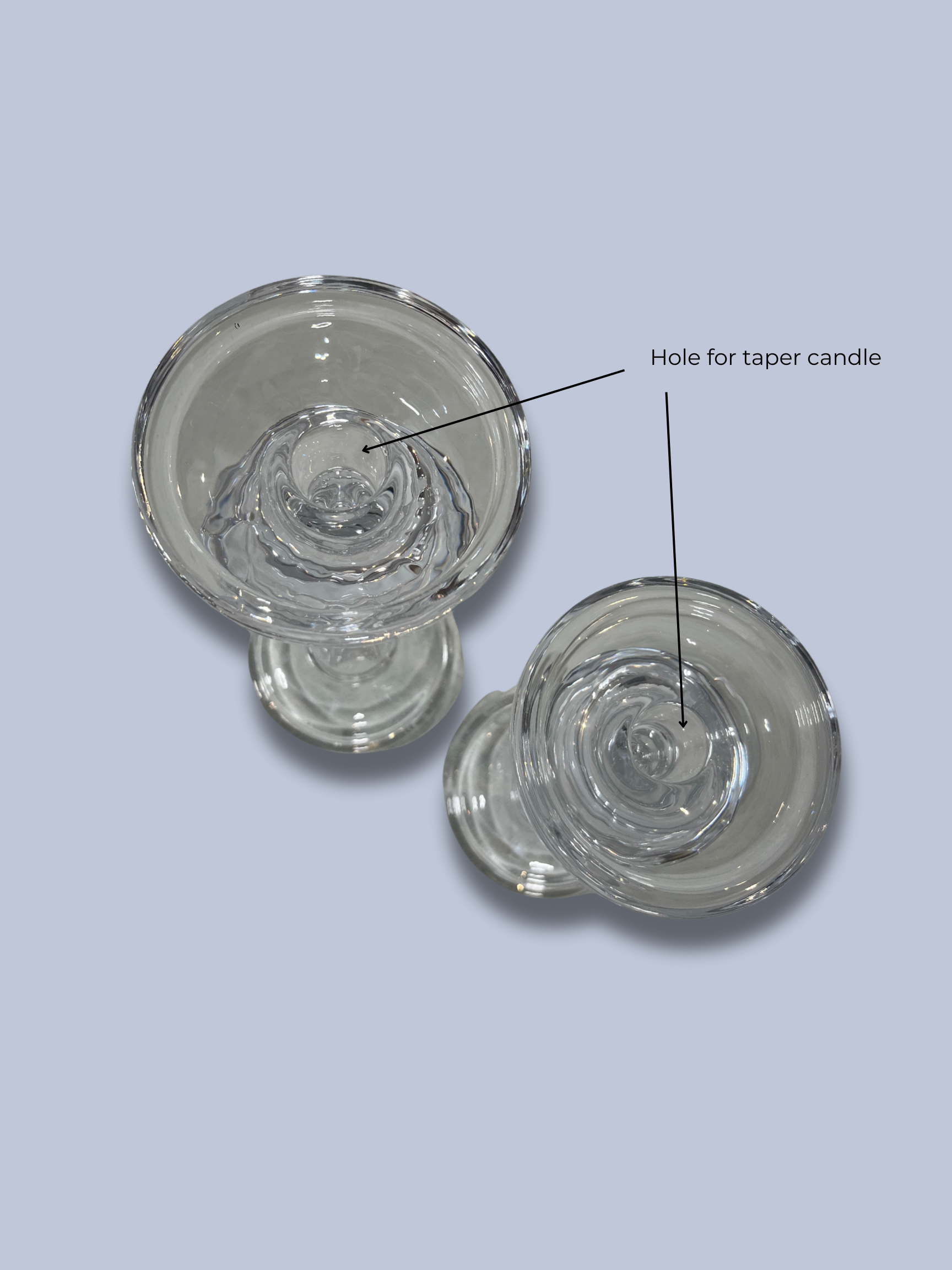 Two glass candle holders with a labeled hole for a taper candle on a light gray background