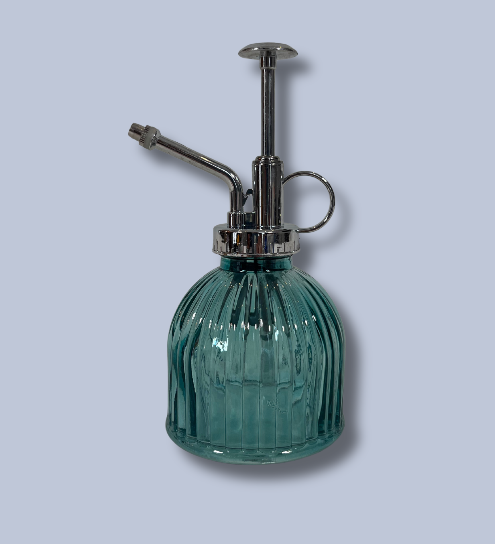 Green glass spray bottle with metal nozzle on a light gray background