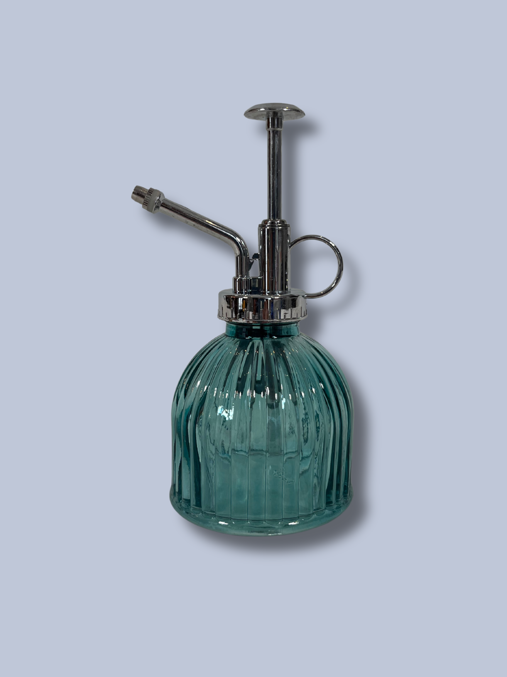 Green glass spray bottle with metal nozzle on a light gray background