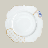 Porcelain white dinner plate with gold and blue floral patterns on a soft green background