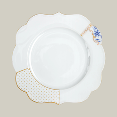 Porcelain white dinner plate with gold and blue floral patterns on a soft green background