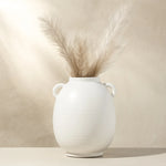 White vase with dried pampas grass against a beige background