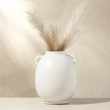 White vase with dried pampas grass against a beige background