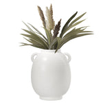 White vase with green leaves and brown dried elements on a white background