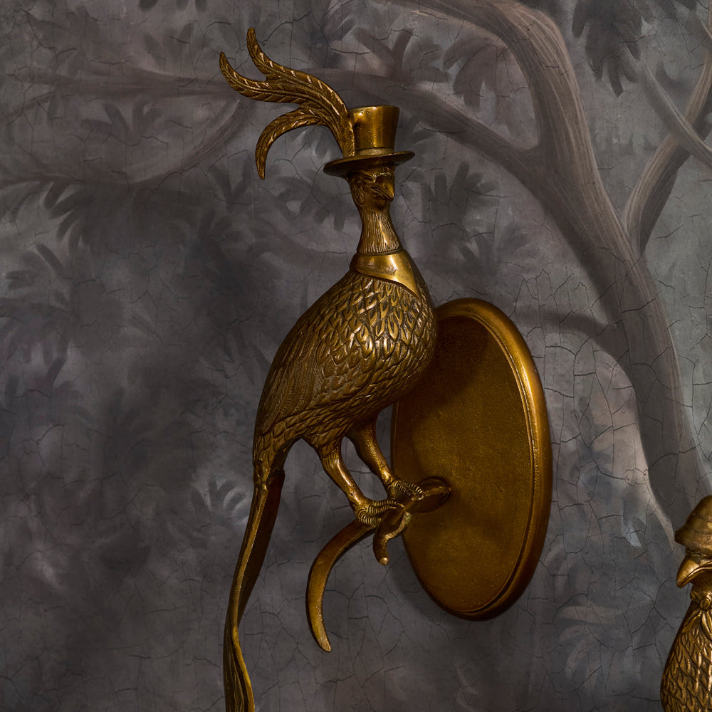 Gold bird-shaped wall sconce on a textured gray wall