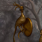 Gold bird-shaped wall sconce on a textured gray wall