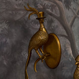 Gold bird-shaped wall sconce on a textured gray wall