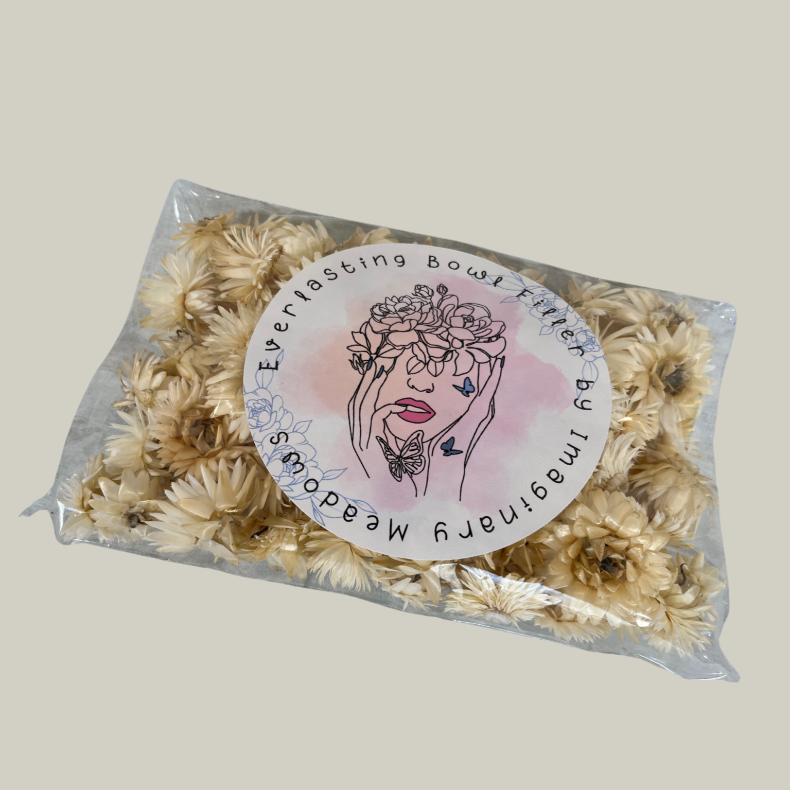 Package of natural cream coloured Hellicrysum floral heads to be used as an everlasting bowl filler In a plastic bag with floral design.