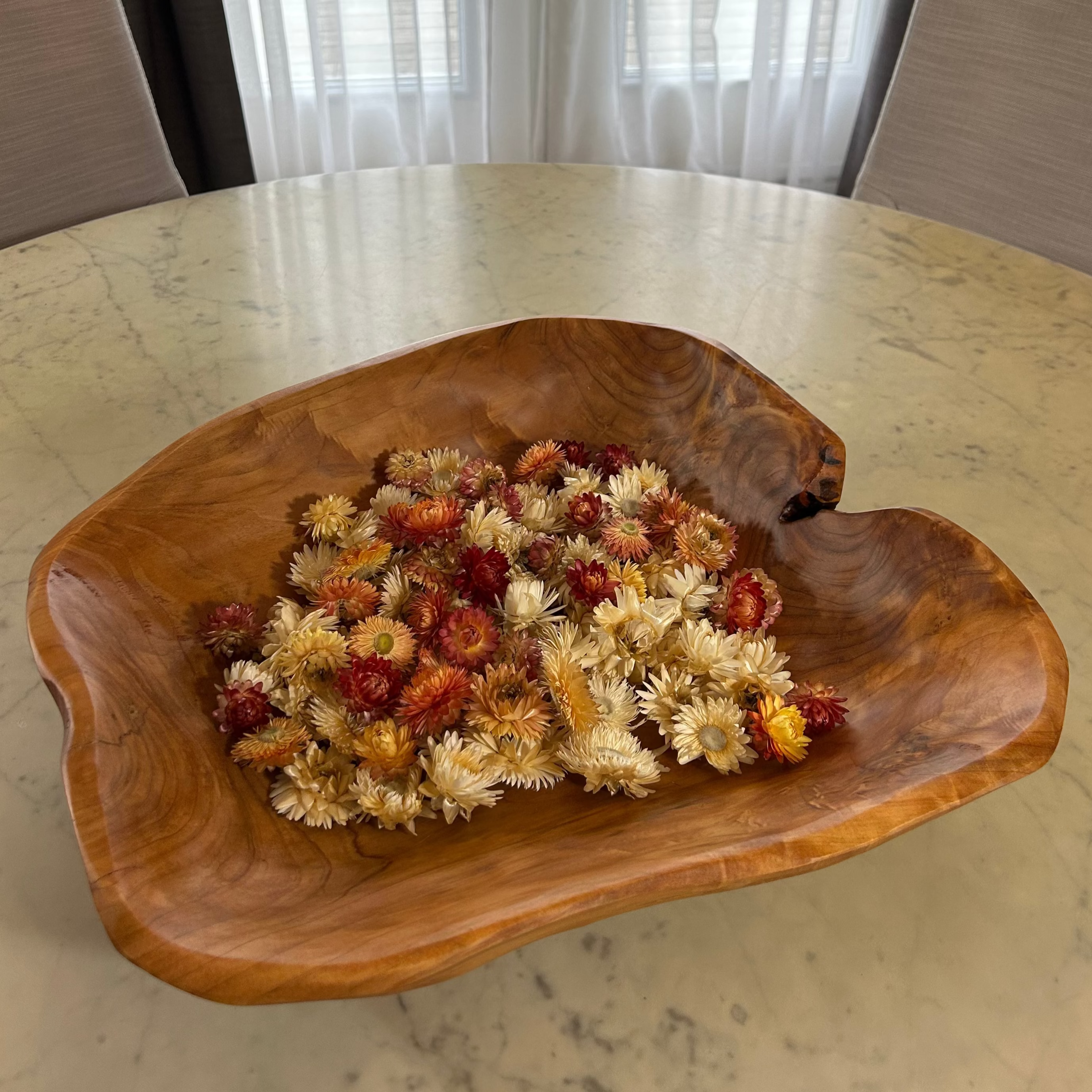 Beautiful hand carved Forest Legacy Bowl made from a fir stump left over from logging industry, filled with dried helichrysum flowers sitting on marble table.