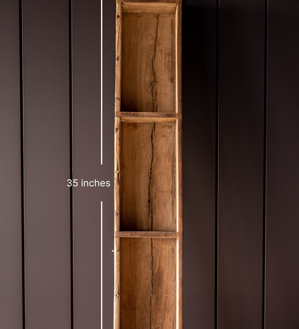 Front view of a tall vintage wooden brick mold standing on it's end against a dark panelled wall with measurements of 35 inches in length