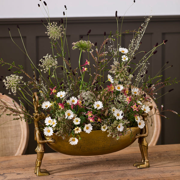 Decorative brass bowl with floral arrangement on a wooden surface