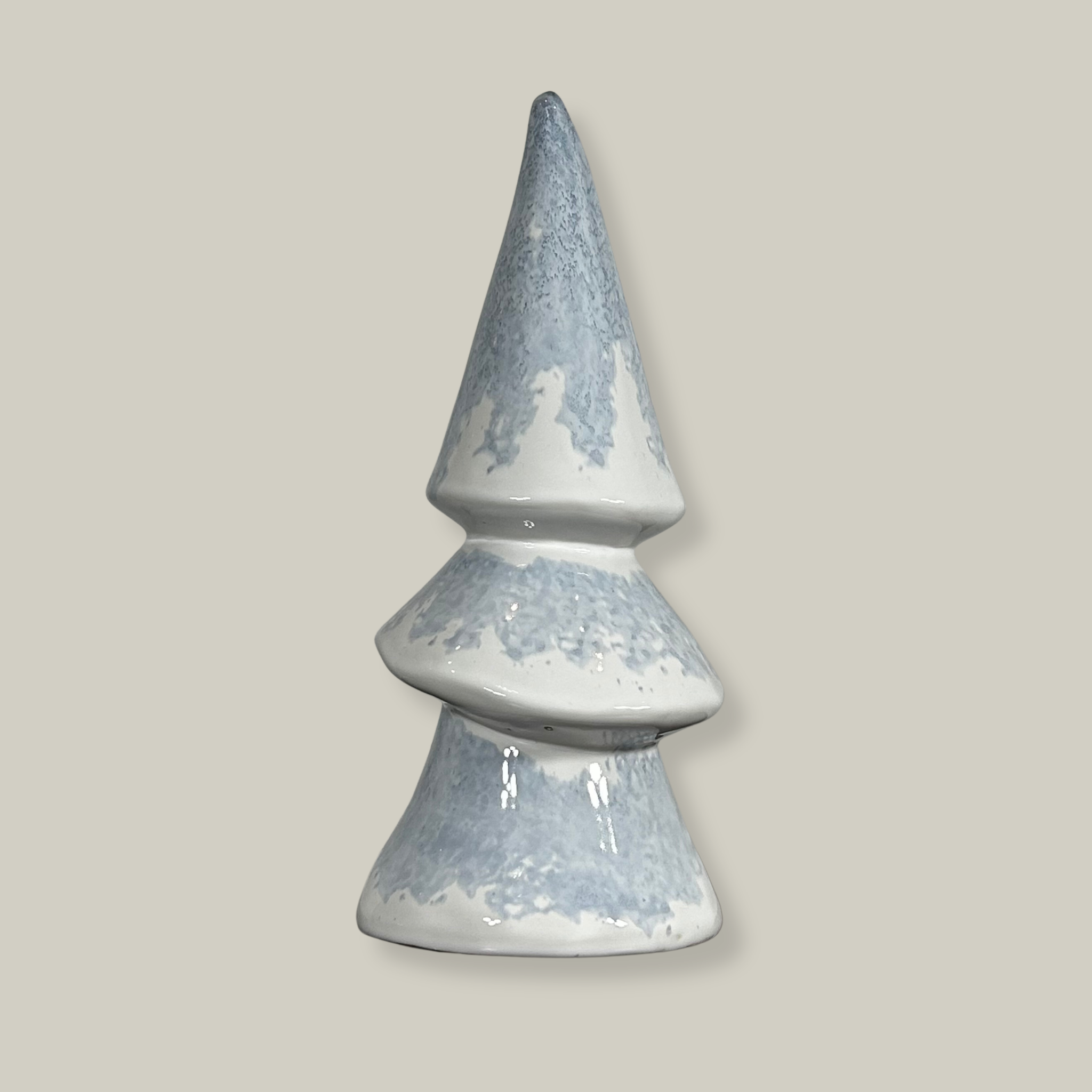 A ceramic Christmas tree figurines with an elegant ivory ceramic surface features an icy blue glaze, meticulously drizzled on before firing to permanently resemble delicate, captured frost.