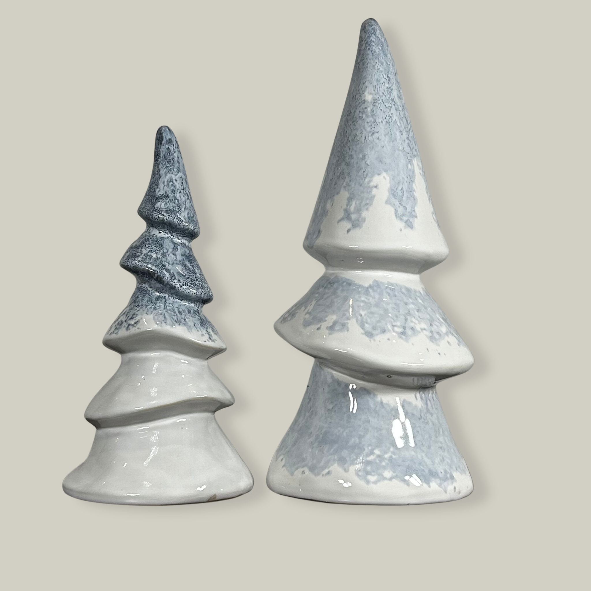 Two ceramic Christmas tree figurines with an elegant ivory ceramic surface features an icy blue glaze, meticulously drizzled on before firing to permanently resemble delicate, captured frost.