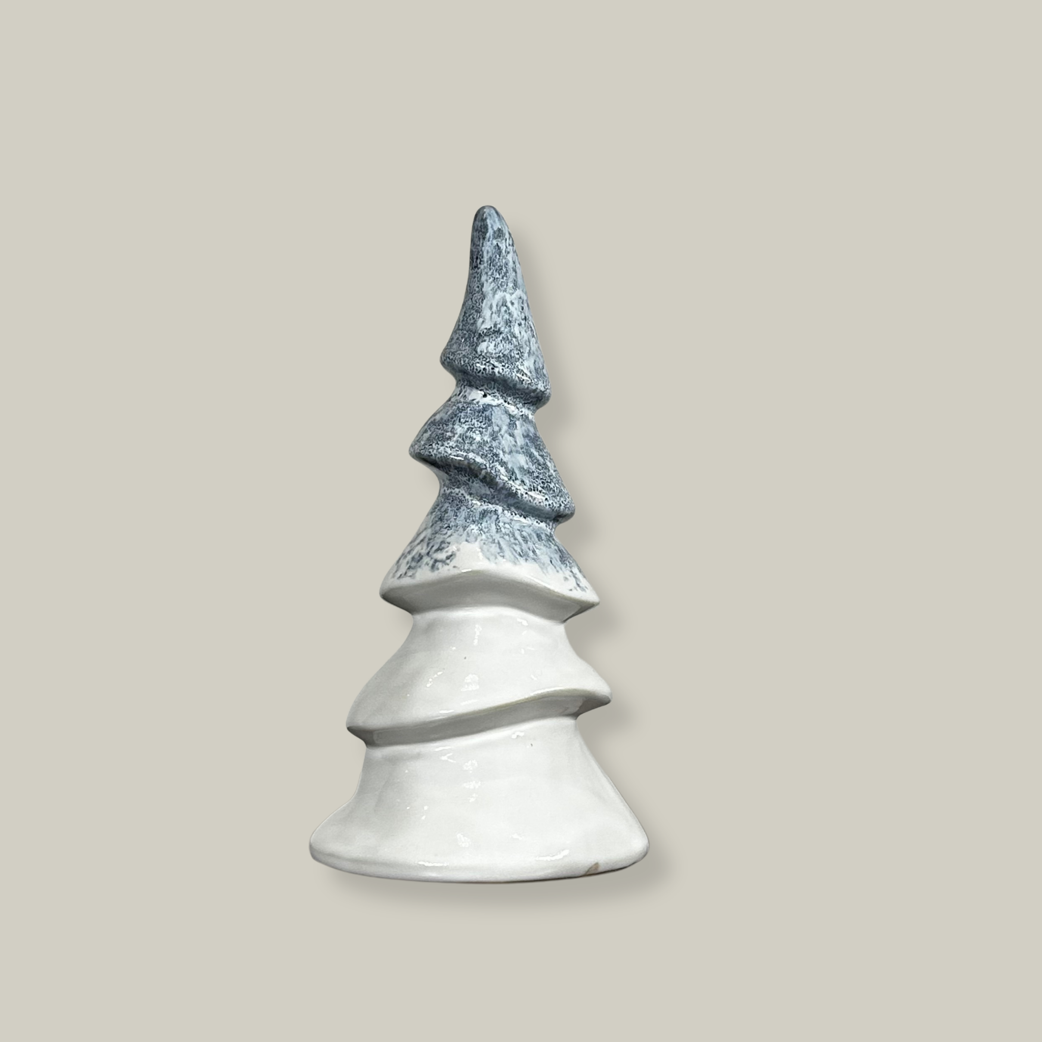 A ceramic Christmas tree figurines with an elegant ivory ceramic surface features an icy blue glaze, meticulously drizzled on before firing to permanently resemble delicate, captured frost.