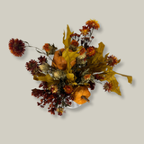 Top view of the arrangement features the bold, preserved tones of yellow scarlet oak leaves and the deep, rich crimson of Chuisco Grass. Fiery Carthamus (safflower) and luminous Helichrysums (strawflowers) in golden and orange tones add a radiant glow. The arrangement is completed with three small pumpkins, perfectly nestled within the blooms.
