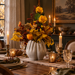 Dining table set out for dinner with a beautiful floral arrangement in the centre made from dried flowers held in a concrete vase carved into four hands in a circle. 1