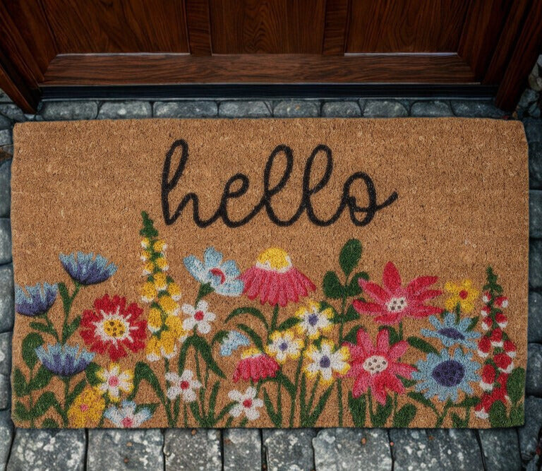 Doormat with floral design and 'hello' text on a stone floor.