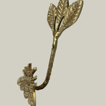 Decorative gold leaf-shaped hook with bee on a beige background