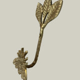 Decorative gold leaf-shaped hook with bee on a beige background