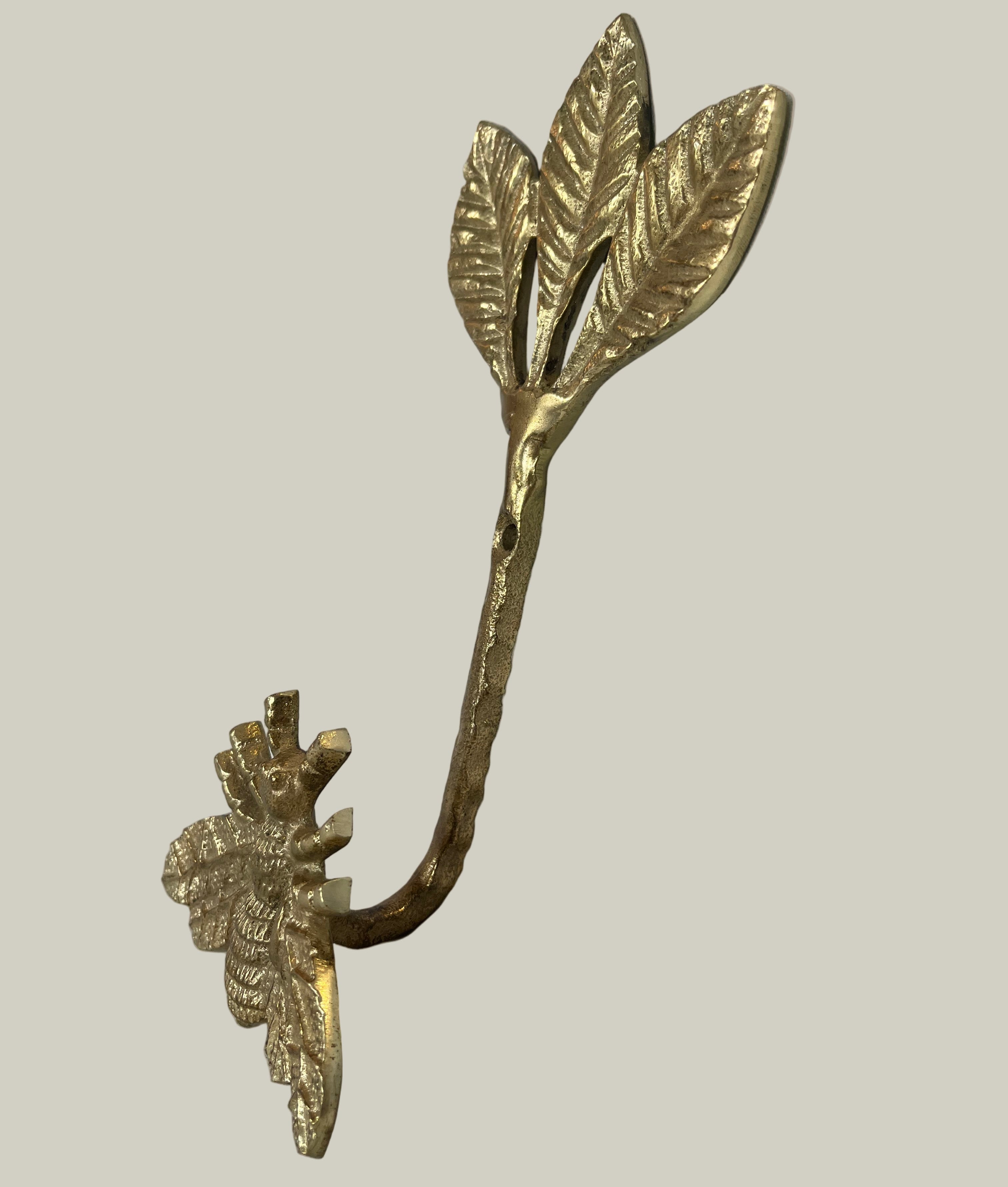 Decorative gold leaf-shaped hook with bee on a beige background