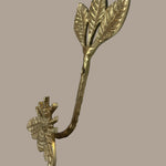 Decorative gold leaf-shaped hook with bee on a beige background