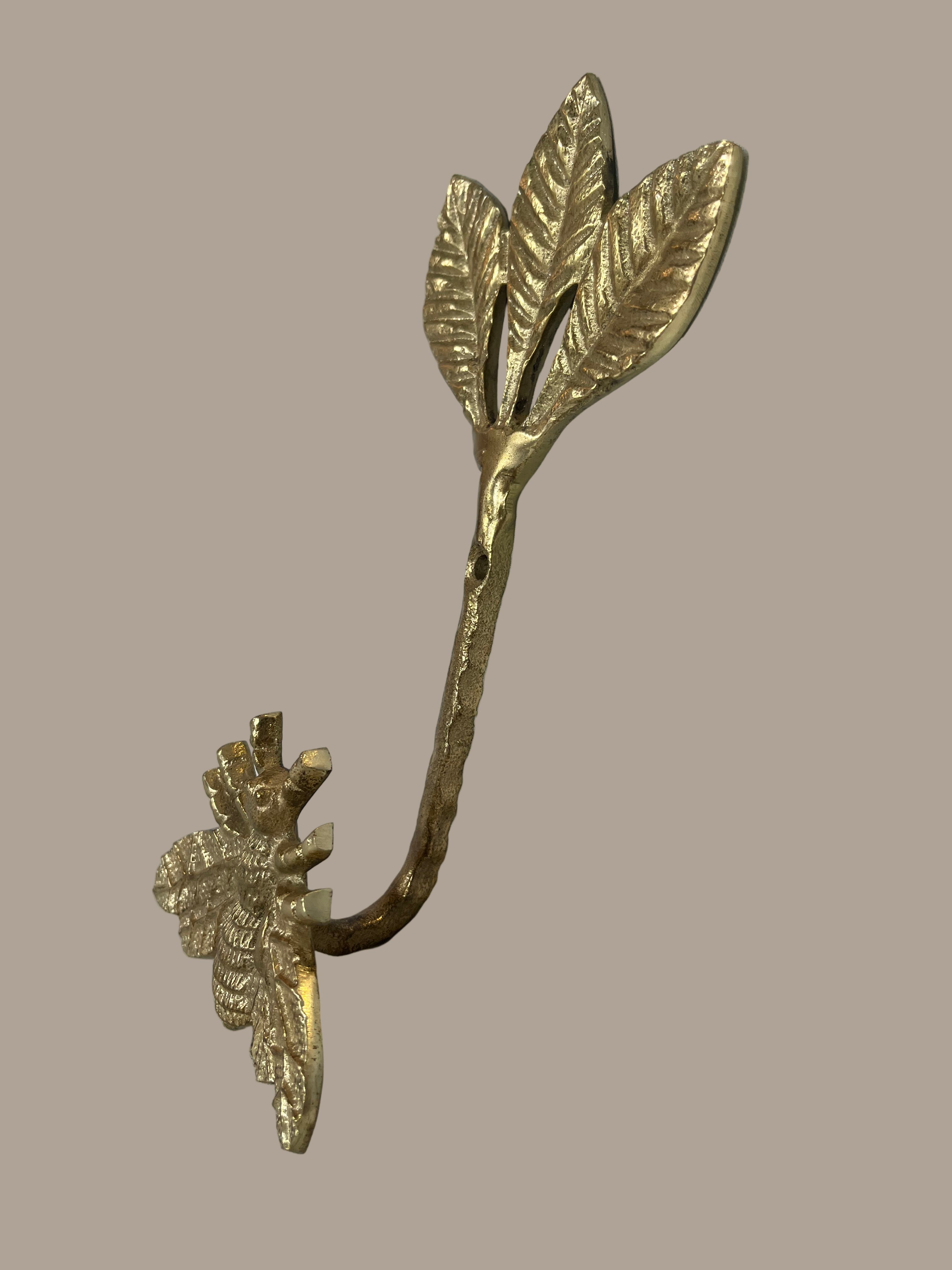 Decorative gold leaf-shaped hook with bee on a beige background