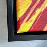 Close-up of a framed artwork with a black frame on a gray surface.
