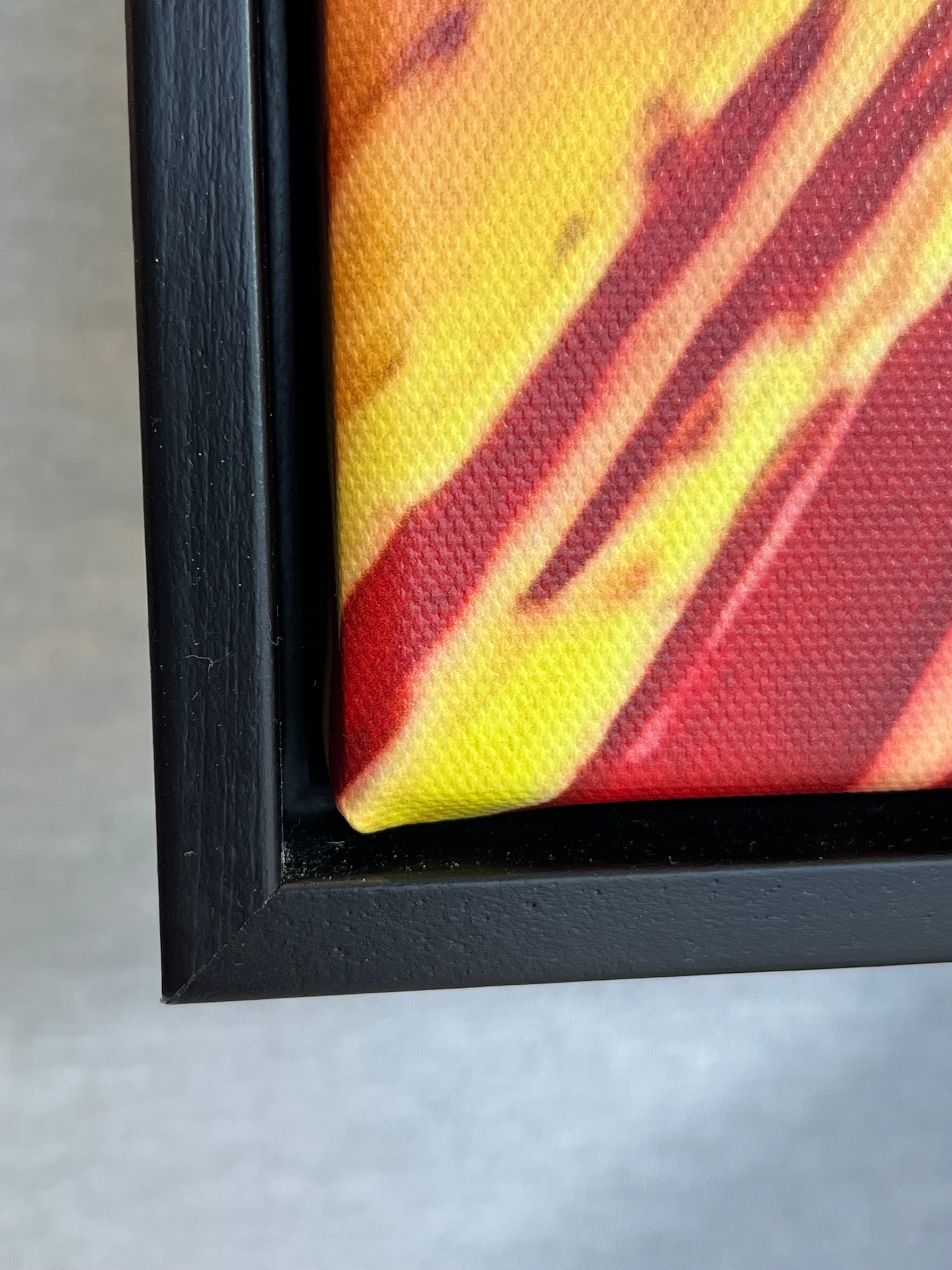 Close-up of a framed artwork with a black frame on a gray surface.