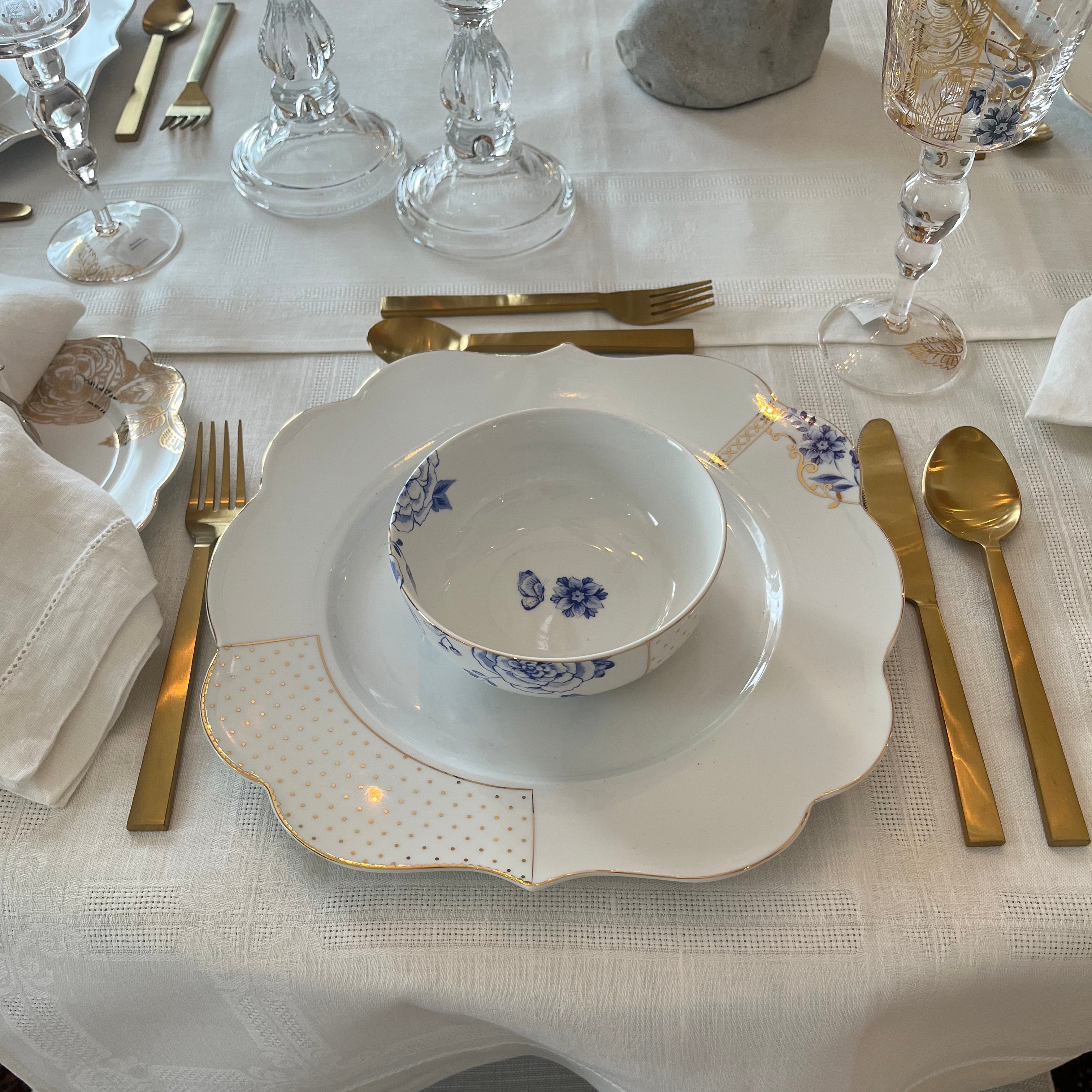 Elegant table setting featuring Pip Studio Royal White dinnerware and Royal Floral wine glasses, our Gilded Ribbon flatware, and a dried floral arrangement as a centrepiece.