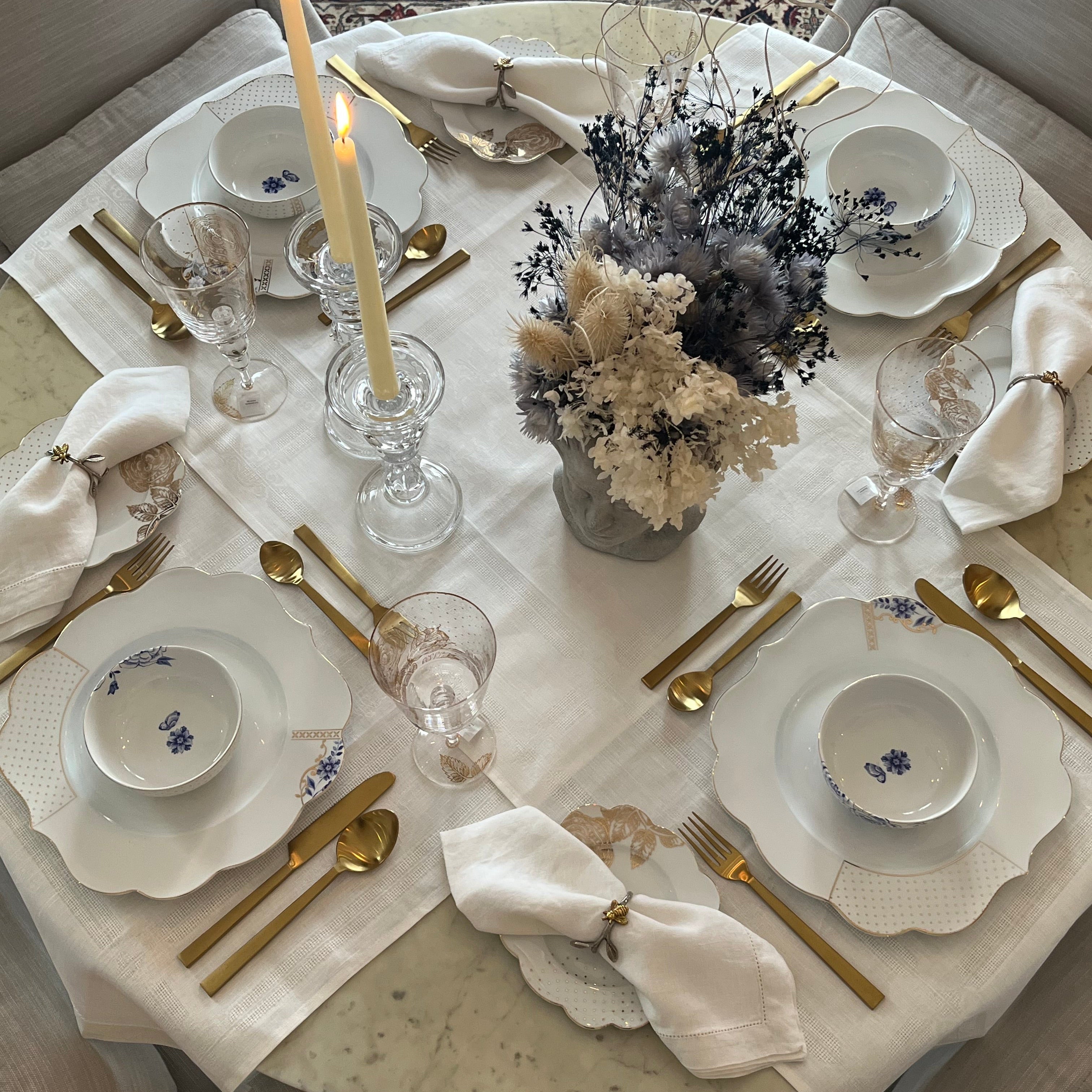 Elegant table setting featuring Pip Studio Royal White dinnerware and Royal Floral wine glasses, our Gilded Ribbon flatware, and a dried floral arrangement as a centrepiece.