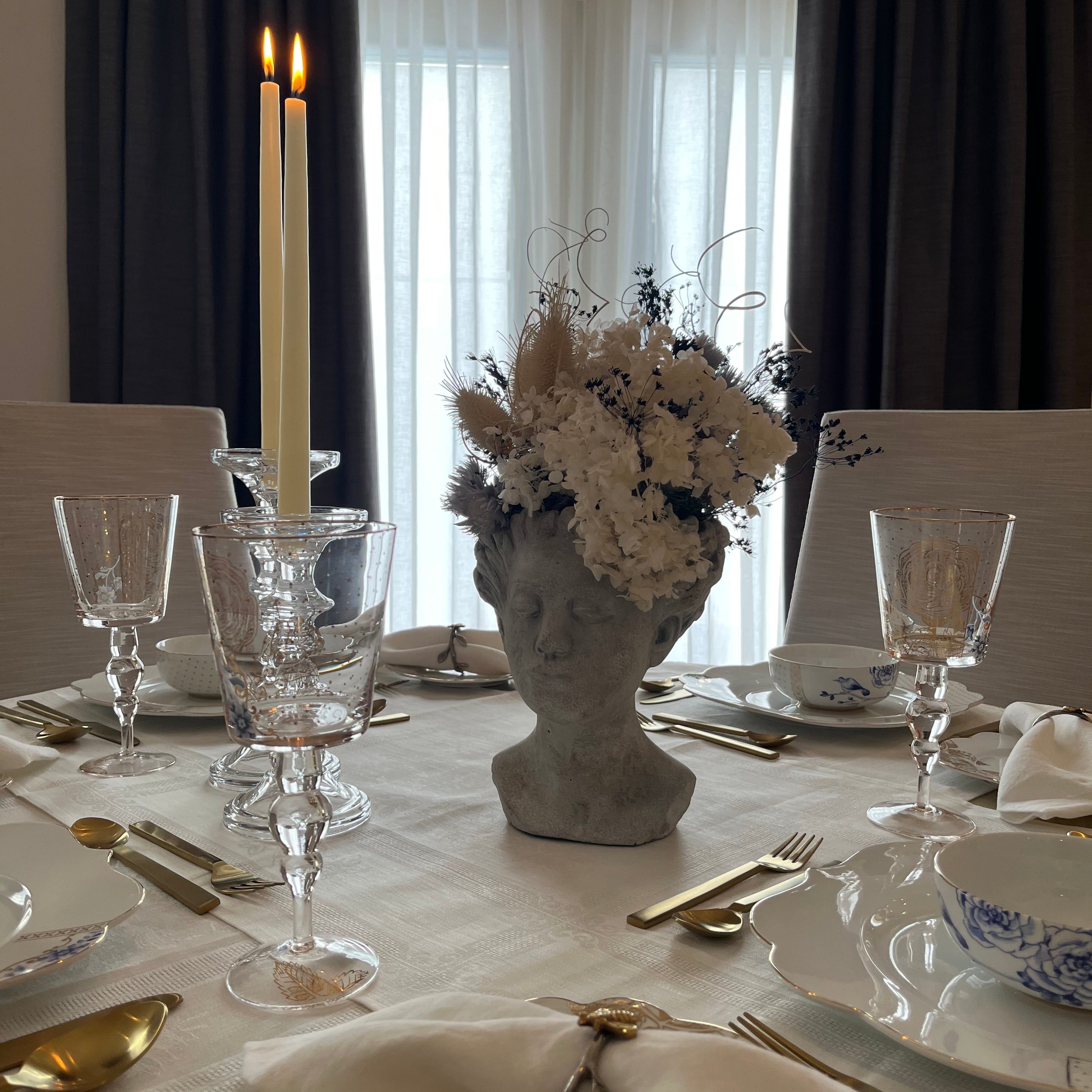 Elegant table setting featuring Pip Studio Royal White dinnerware and Royal Floral wine glasses, our Gilded Ribbon flatware, and a dried floral arrangement as a centrepiece.