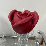 A beautiful handcrafted candle with intricate detailing of a red rose shape made from 100% pure vegan soy wax displayed on a glass candlestick.
