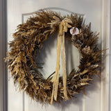 This impressive 28 inch wreath is made with the elegance of spider wood and the airy lightness of Star Grass. It is a rich tapestry of grains, including the unique forms of Sorghum, dried Rice Ears, and graceful Arena Wild Oats. Sculptural bleached cane cones and the whimsical twists of bleached curly ting ting add the final, enchanting touches.

