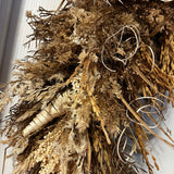 A close-up of this impressive 28 inch wreath is made with the elegance of spider wood and the airy lightness of Star Grass. It is a rich tapestry of grains, including the unique forms of Sorghum, dried Rice Ears, and graceful Arena Wild Oats. Sculptural bleached cane cones and the whimsical twists of bleached curly ting ting add the final, enchanting touches.