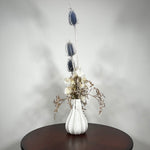 Vase of dried floral arrangement made with delicate, lace-like petals of white Cape Flowers against the intriguing, sculpted heads of blue Teasels. Adding airy lightness and enduring colour is German Statice. 