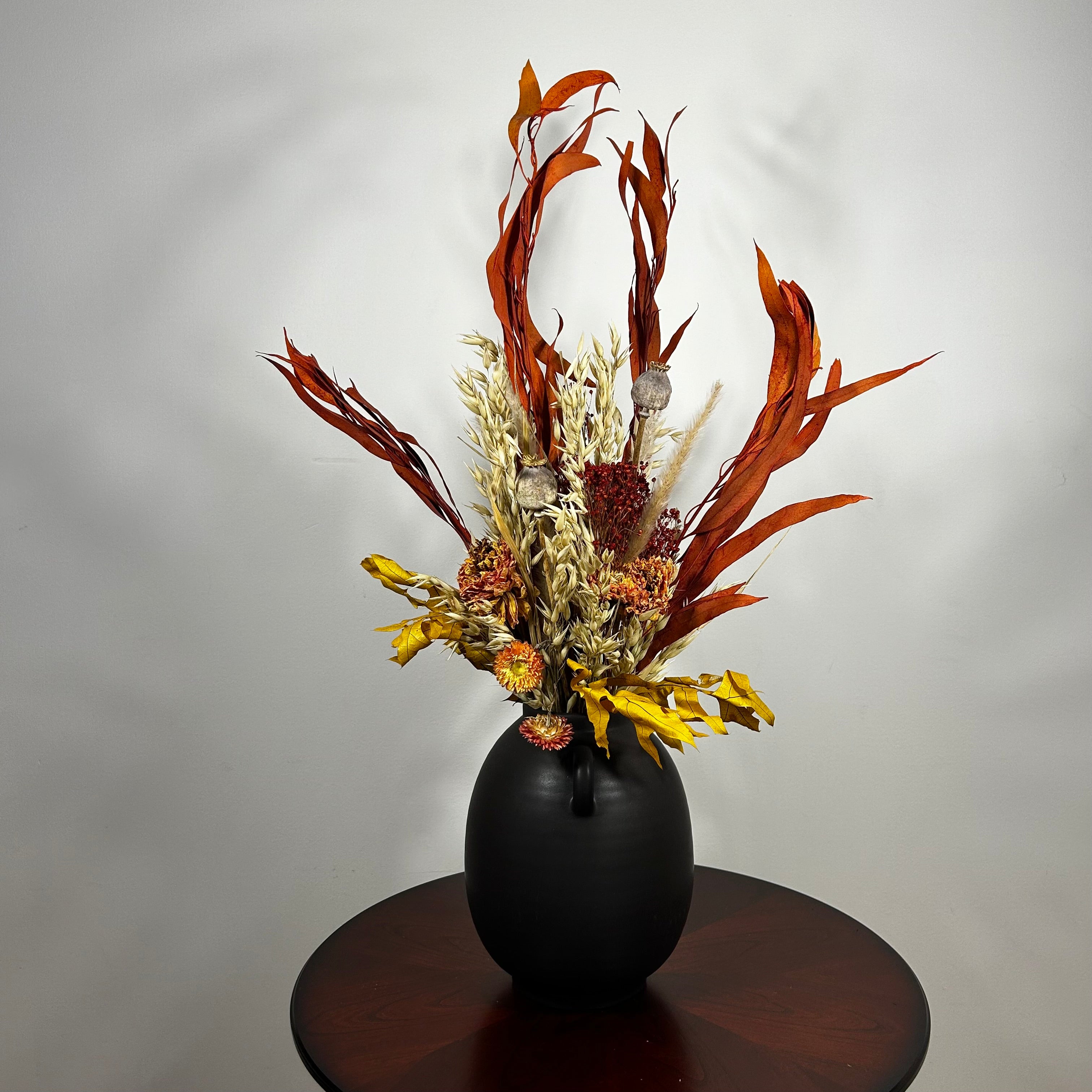 A magnificent 30" dried floral arrangement with autumn botanicals like helichrysum, dahlias, & oak leaves in a matte brown urn.