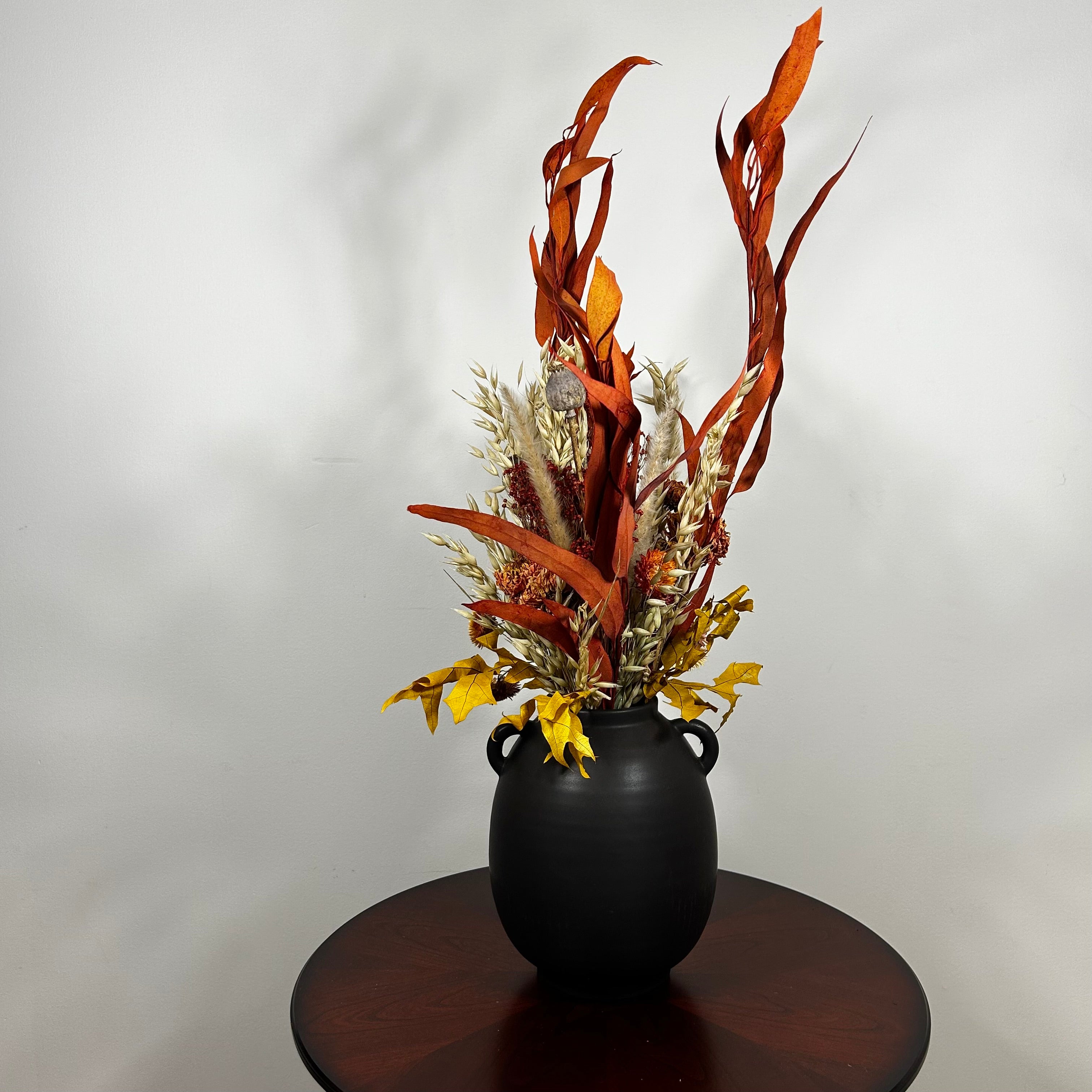 A magnificent 30" dried floral arrangement with autumn botanicals like helichrysum, dahlias, & oak leaves in a matte brown urn.