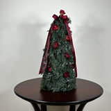Decorative Christmas tree this 18-inch design is densely layered with fragrant, preserved Juniper and its signature blue berries, with beautiful deep red "Bright Torch" roses are placed to command attention. The entire piece is finished with a large, elegant deep red grosgrain double bow, whose ribbons cascade down.