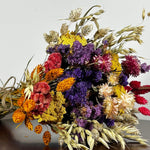 This magnificent, hand-tied bouquet is a vibrant symphony of contrasting colours and textures designed for the sophisticated interior. The Amethyst base of lush purple Statice provides a dramatic backdrop for the Gold accents: bright yellow Achillea Parker and soft natural pink Helichrysums. Textural elements featuring the unique, wavy shapes of red coral Celosia and Phalaris dyed in three complementary colors (natural, orange, and red).
