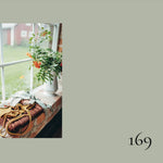 Floral arrangement on a windowsill with a number '169' on a plain background